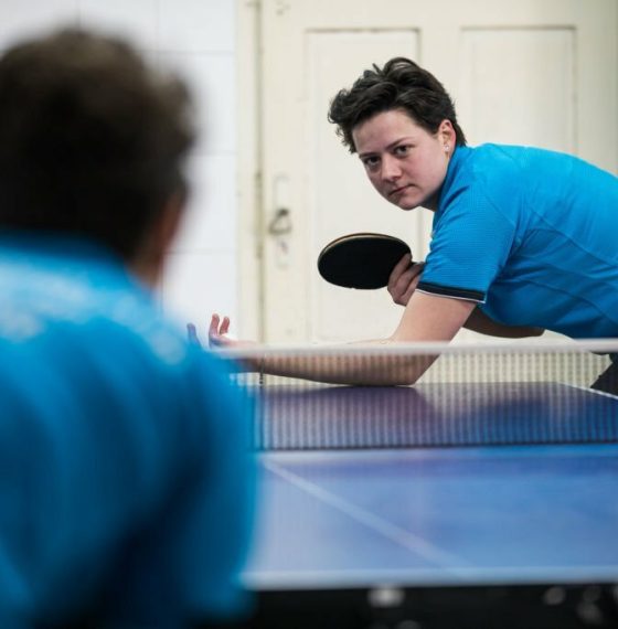 Concentrated young woman playing table tennis indoors